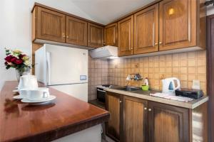 a kitchen with wooden cabinets and a white refrigerator at Areti Apartments in Póros Kefalonias