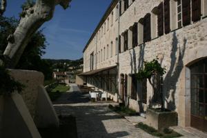 a building with tables and chairs next to a street at La Magnanerie de Seillans in Seillans