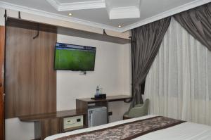 a hotel room with a bed and a flat screen tv at Lagos Hotel in Nairobi