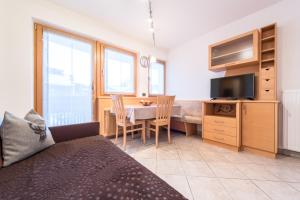 a bedroom with a desk and a table with a television at Ciasa Mascotte in San Vigilio Di Marebbe