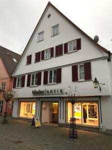 un edificio blanco con persianas rojas en una calle en Stadt Apartment, en Günzburg