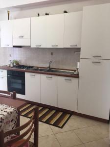 a kitchen with white cabinets and a sink and a table at Cordovena in Capo dʼOrlando