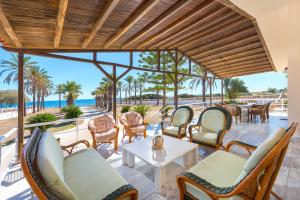 un patio con sillas y mesas y vistas al océano en Villa Maria Beachfront Residence en Kiotari