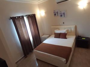1 dormitorio con 1 cama grande y cortinas marrones en Hôtel YABISSO, en Lomé