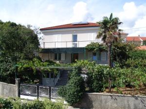 a house with a palm tree in front of it at Sobe Bozica in Krk