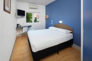 a white bed sitting in a bedroom next to a wall at ibis Budget Perth Airport in Perth