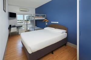 a bedroom with a bed and a desk and a blue wall at ibis Budget Perth Airport in Perth +20 photos