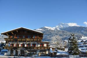 ein großes Gebäude im Schnee mit Bergen im Hintergrund in der Unterkunft Kaiserhotel Neuwirt in Oberndorf in Tirol