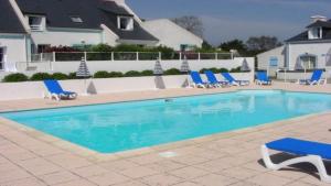 - une piscine avec des chaises longues bleues dans l'établissement Maison avec vue sur mer dans Résidence Marie Galante, à Locmaria