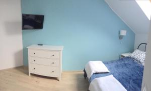 ダルウフコにあるSłoneczny Apartamentの青い壁のベッドルーム1室、ベッド1台、ドレッサーが備わります。
