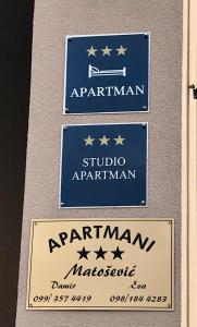 three signs on the side of a building at Apartmani Matosevic in Ivankovo