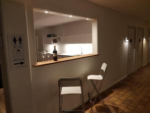 una cocina con 2 sillas y una barra con una botella de vino en Klintholm Marina Park Cabins, en Borre