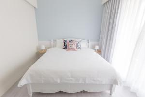 a bedroom with a white bed with white curtains at Let's Go Papa in Taitung City