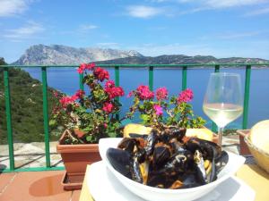 a bowl of mussels on a table with a glass of wine at Villaggio Est a Capo Coda Cavallo San Teodoro in San Teodoro