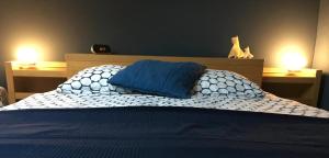 a bed with two blue pillows on top of it at Les Jardins de l'Ile in Longeville-lès-Metz
