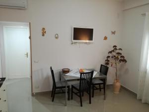 a dining room table with chairs and a television on the wall at La Casa del Professore in Santa Teresa di Riva