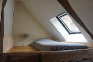 a bed in a attic with a window at l'entresort in Aubusson