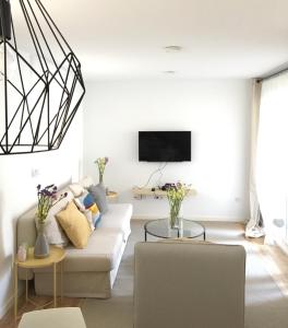ein Wohnzimmer mit einem weißen Sofa und einem TV in der Unterkunft Apartment Santa Teresa in Altea