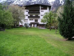 a large white building with a green yard with trees at Pension Garni Ötztalerhof in Sautens