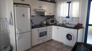 a kitchen with white cabinets and a washer and dryer at Rita SeaView Apartment in Perivolia