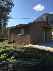 a small brick house with a mountain in the background at A Casetta di Rosa in Corte