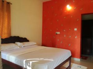 a bedroom with two beds and a red wall at La Mirban in Varkala