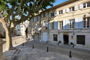 a street scene with a building and trees at Hotel De L'Atelier in Villeneuve-lès-Avignon