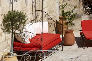 a red bench sitting on a patio with potted plants at Hotel De L'Atelier in Villeneuve-lès-Avignon