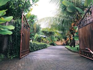 an open gate in a garden with palm trees at El Homestay Bali in Nusa Dua