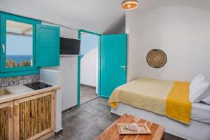 a bedroom with a bed and a kitchen with green cabinets at Nissia Beach Apartments & Suites in Kamari
