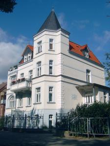un grand bâtiment blanc avec un toit rouge dans l'établissement Pension Villa Beer, à Stralsund
