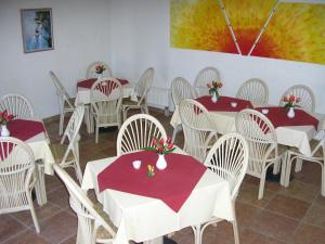 uma sala de jantar com mesas brancas e cadeiras brancas em Pension Villa Beer em Stralsund