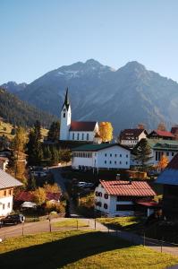 a small town with a white church with mountains in the background at Herzen´s Landhaus in Hirschegg