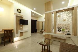 a large living room with a television and a table at Hotel Alka Inn in Ahmedabad