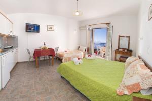 a bedroom with a green bed and a kitchen and a table at Summer Dream in Vlachata