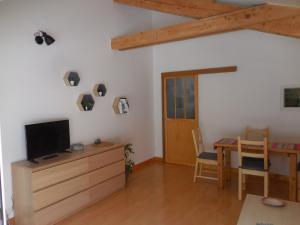 a living room with a television on a dresser and a table at Gîte Toukoul in Autrans