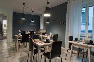 a dining room with tables and chairs and windows at Relais Merizzi in Tirano