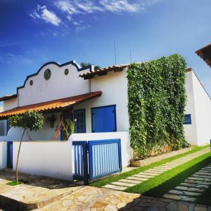 ein weißes Haus mit blauer Tür und Hecke in der Unterkunft Chalés de São José - Casas de Aluguel in Tiradentes