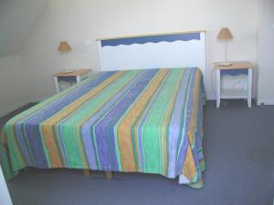 a bedroom with a bed with a colorful striped bedspread at Maison avec vue sur mer dans Résidence Marie Galante in Locmaria