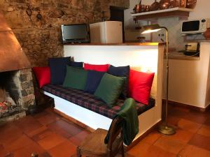 a couch with colorful pillows on it in front of a fireplace at Casa do Tôjo e Rosmaninho in Ferreira do Zêzere