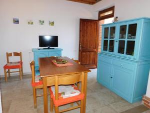 una cucina con armadi blu, tavolo e TV di Diletta a Cala Liberotto