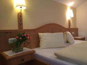 ein Schlafzimmer mit einem Bett mit einer Vase aus Blumen auf dem Tisch in der Unterkunft Gasthof Botenwirt in Faistenau