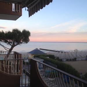 uma vista para a praia ao pôr-do-sol a partir da varanda de um hotel em Sea view apartment with swimming pool em Lido di Jesolo