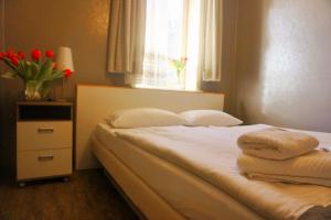 Un dormitorio con una cama con flores rojas en una ventana. en Pharos zur Seeve, en Seevetal