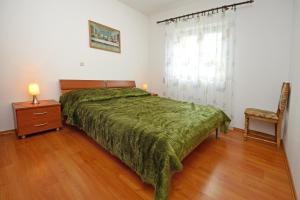 een slaapkamer met een groen bed en een houten vloer bij Apartmani KRAMAR in Poreč