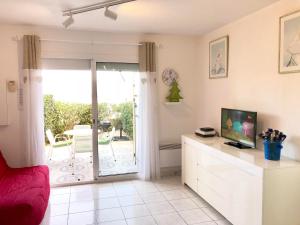 uma sala de estar com uma televisão e uma porta de vidro deslizante em Barcaresa-Villa Vue Mer Accès Direct Plage - Piscine em Le Barcarès