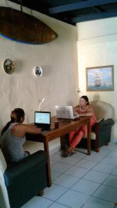 two women sitting at a table with their laptops at Lorena Surf Hostel in San Juan del Sur