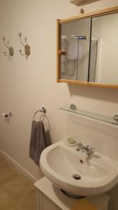 a white bathroom with a sink and a mirror at Katrinas Apartment By Treetop Property in Cirencester