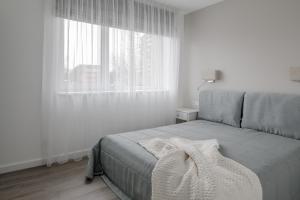 a white bedroom with a bed and a window at Comfort Stay - Klaipeda in Klaipėda