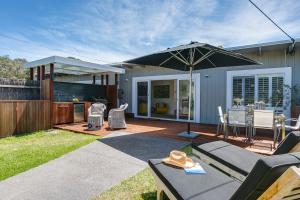 un patio trasero con un patio con sombrilla en Capella Villa No. 2 - luxury with outdoor kitchen, en Blairgowrie